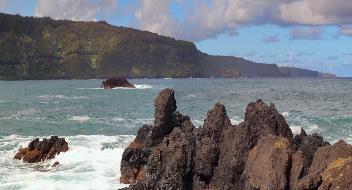 A rocky beach with a hill in the background at Keʻanae Peninsula