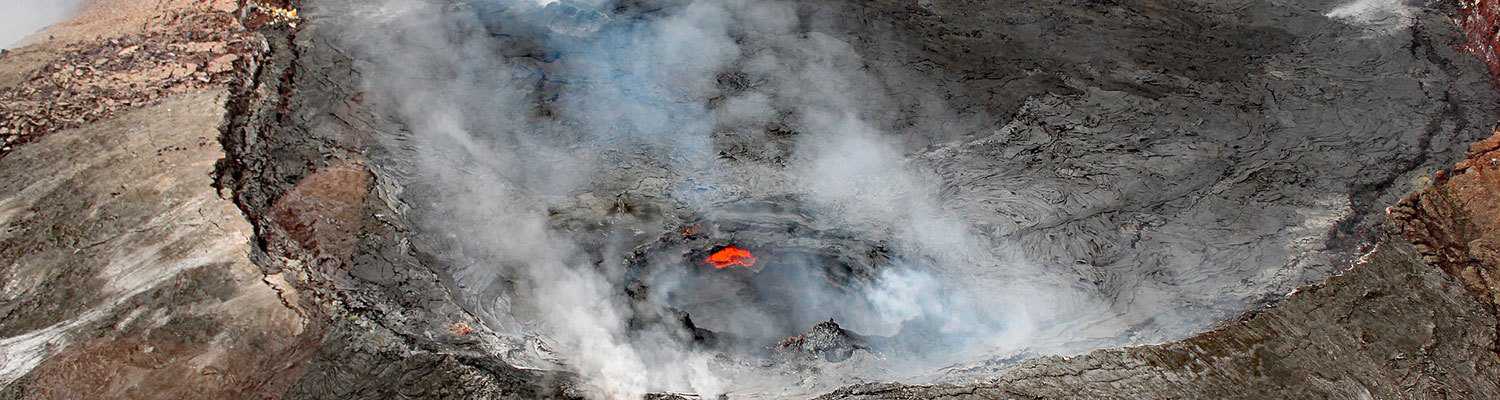 Aerial view of steam rising from a glowing volcanic crater