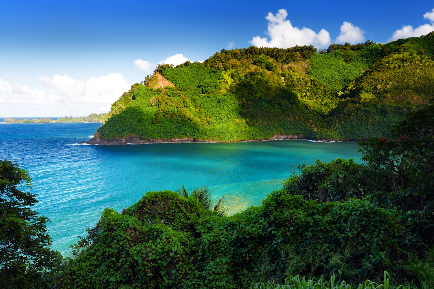 Turquoise bay below green cliffs on the Maui coast