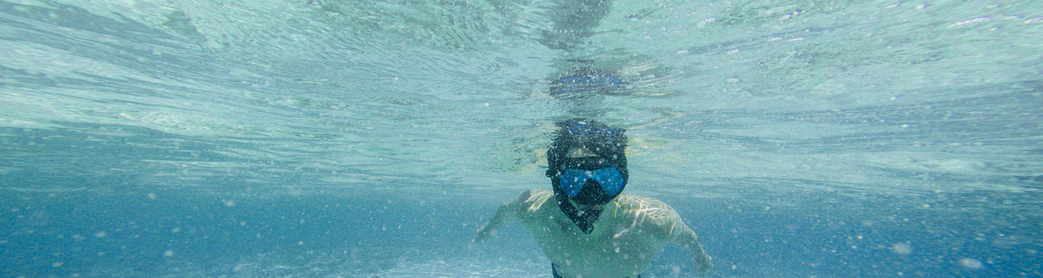 Snorkeler in a mask swimming in clear blue water