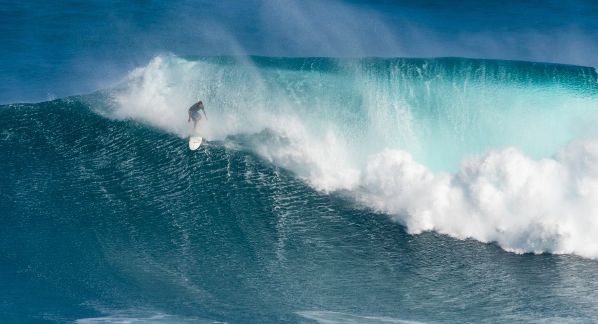 Professional big wave surfer riding massive 40-foot wave at Peʻahi Jaws surf break on Maui's north shore
