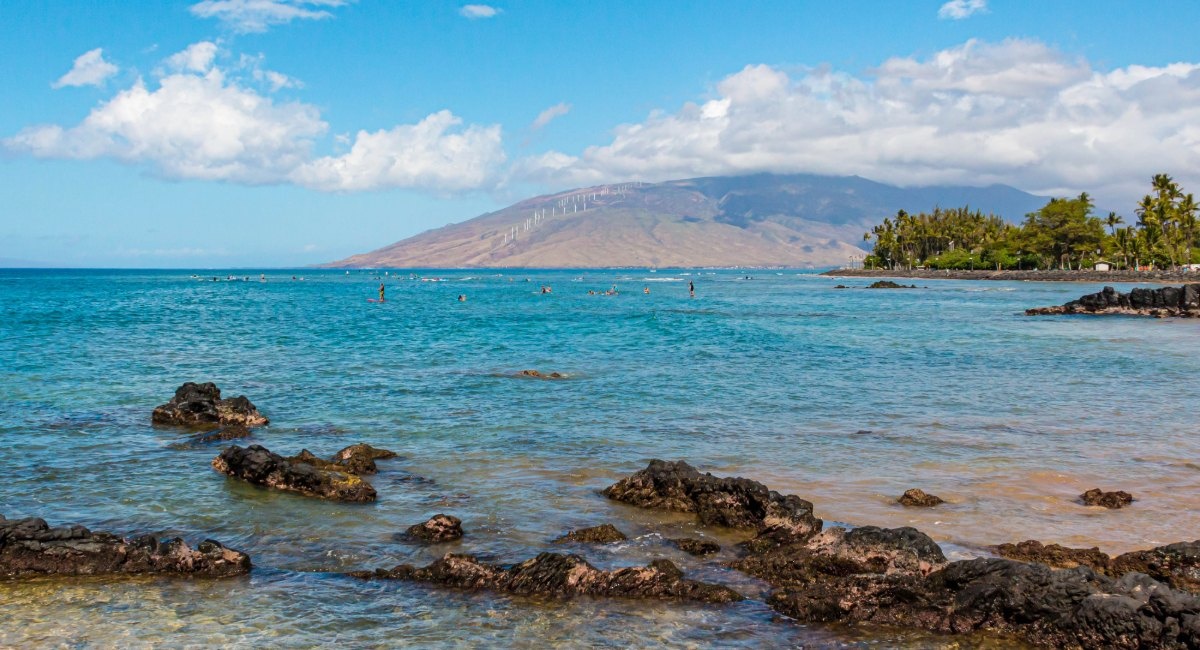 Beginner surfers learning at The Cove Kalama Beach Park Kīhei with calm turquoise waters and West Maui Mountains backdrop